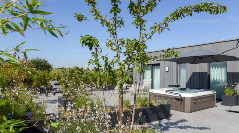 Luxe daktuin/dakterras bij een penthouse, met jacuzzi, bloemenborders, bomen en siergrassen.